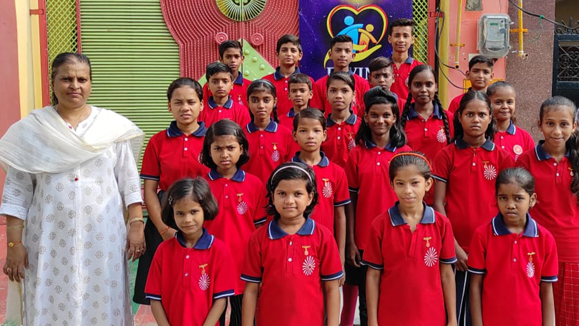 Group of Divine Sanskarshala students in red uniforms standing with founder Lata Agrawal