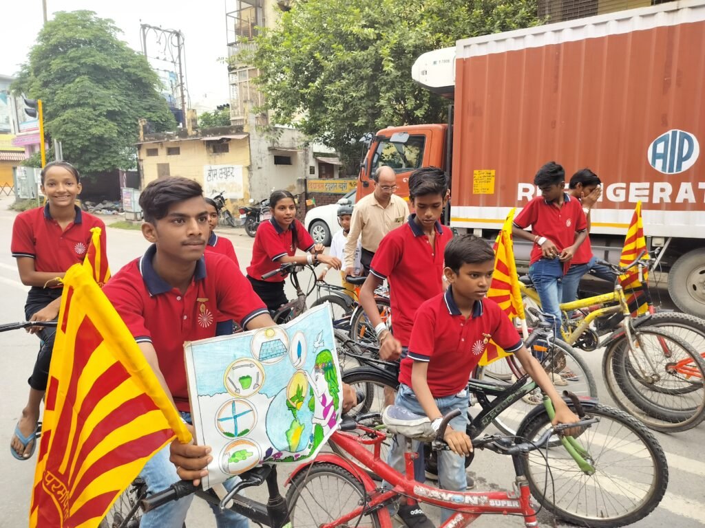 Children of Divine Sanskarshala in red uniforms riding bicycles with flags and posters during a cycle rally to spread awareness.