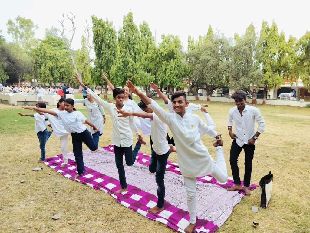 Group of children from Divine Sanskarshala practicing yoga poses together outdoors on a mat, showcasing balance, focus, and harmony.