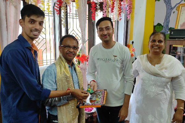 Director of Aisshpra Gems and Jewels visiting Divine Sanskarshala and receiving a handmade artwork and memento from students during a cultural interaction event.