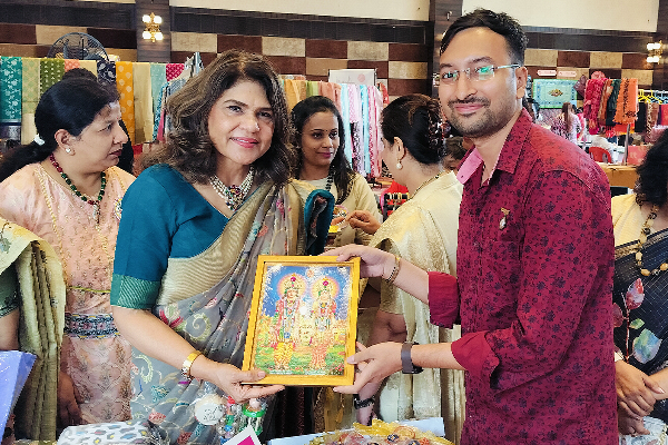 Bharti Madhok, Director of Sunbeam Group of Educational Institutions, receiving a framed devotional artwork from the founder of Divine Sanskarshala during a cultural exhibition event.