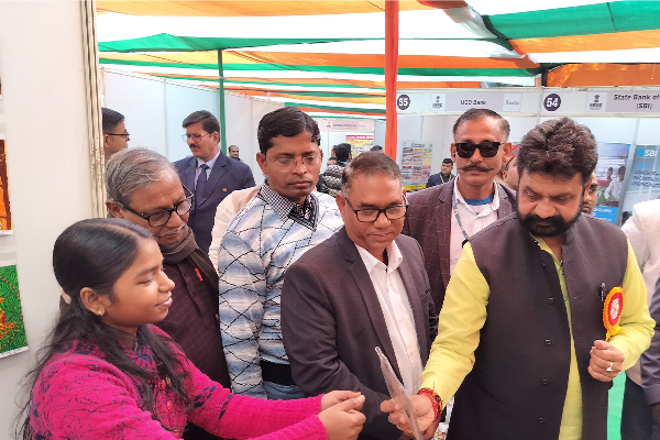 Dr. Daya Shankar Mishra, Hon. MoS for Ayush, Uttar Pradesh, interacting with students and visitors at the Divine Sanskarshala exhibition stall during an event, surrounded by attendees under a colorful canopy.