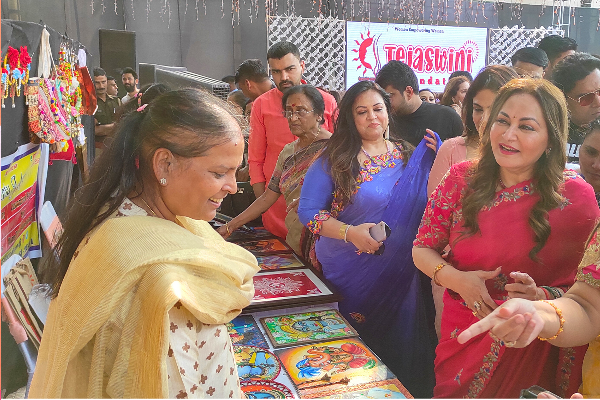 Actress Jaya Prada interacting with members at the Divine Sanskarshala stall while viewing student artwork and creative displays at an exhibition event.
