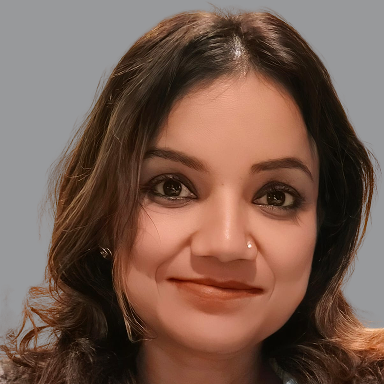 Portrait of Luvly Agrawal, Executive Member of Divine Sanskarshala, with long wavy hair and a gentle smile against a gray background.