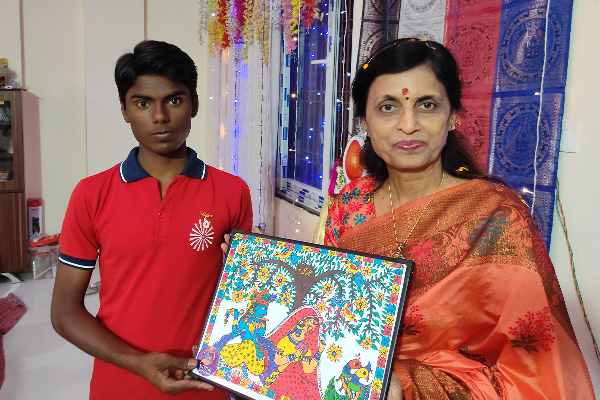 Rachna Agrawal, BJP Varanasi Mahanagar Treasurer, posing with a student from Divine Sanskarshala who is holding a colorful traditional artwork during a cultural interaction event.