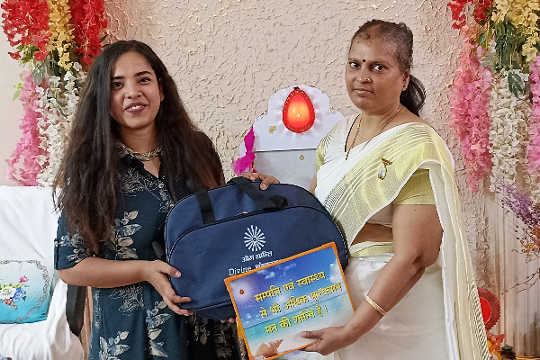RJ Arundhati from Big FM receiving a Divine Sanskarshala gift bag and appreciation plaque during a special recognition event at the institution.