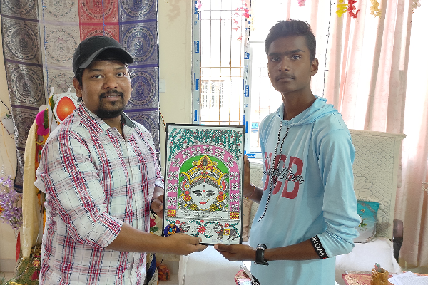 RJ Vishal from Radio City receiving a colorful traditional artwork from a student at Divine Sanskarshala during a cultural appreciation event.