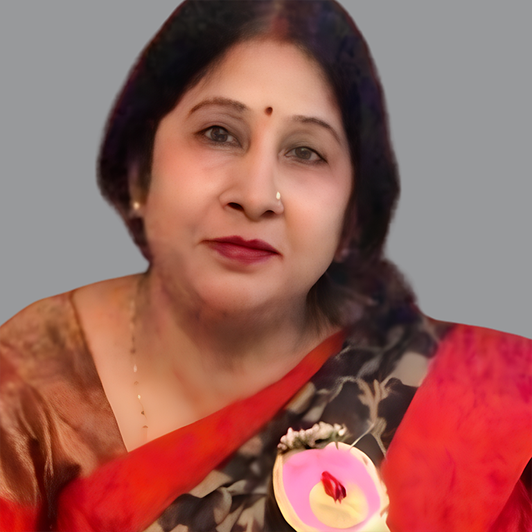 Portrait of Reeta Singh, Executive Member of Divine Sanskarshala, wearing a red and black saree with elegant jewelry and a calm expression against a grey background.