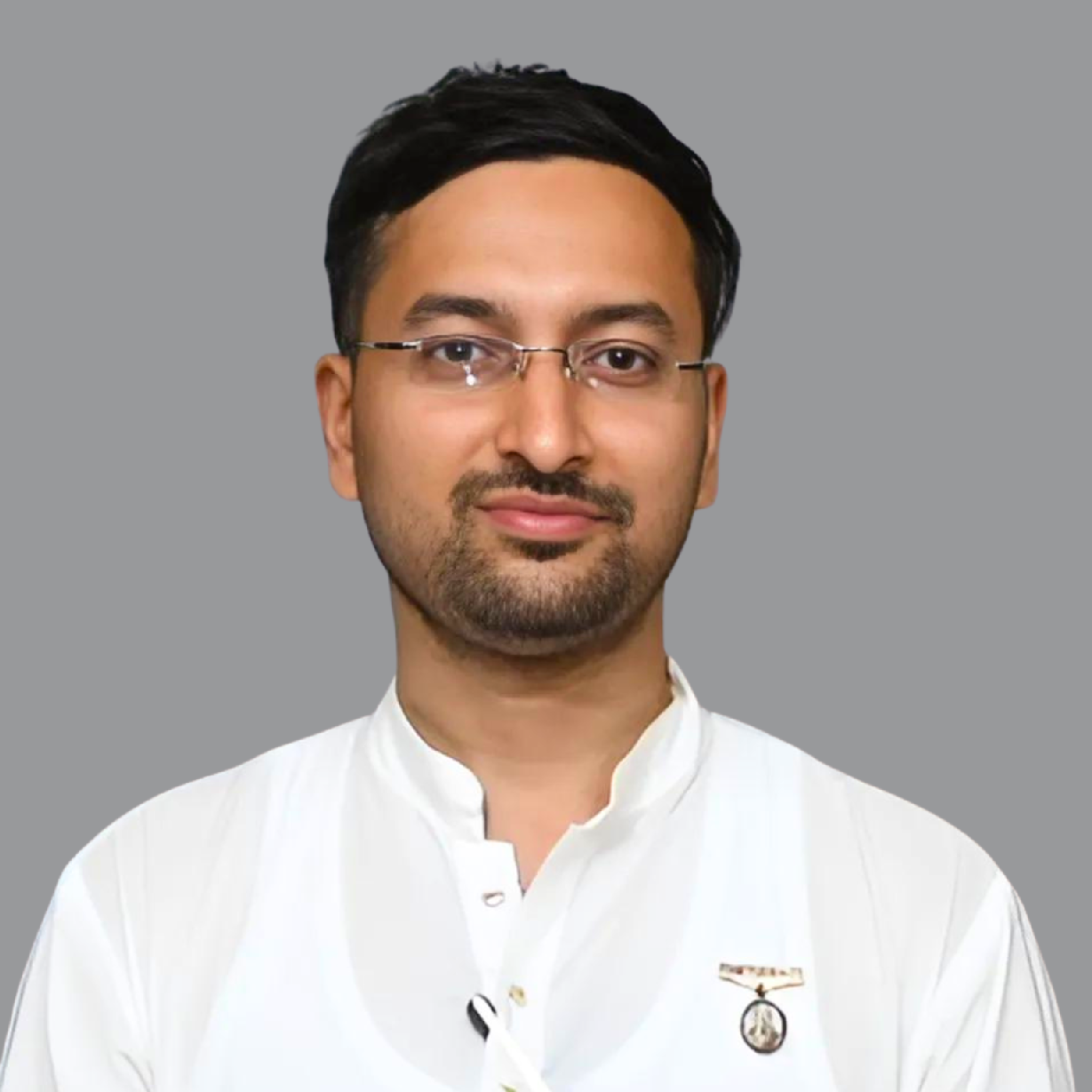 Professional portrait of Yash Agrawal, Secretary of Divine Sanskarshala, wearing a white traditional outfit and glasses against a plain grey background.