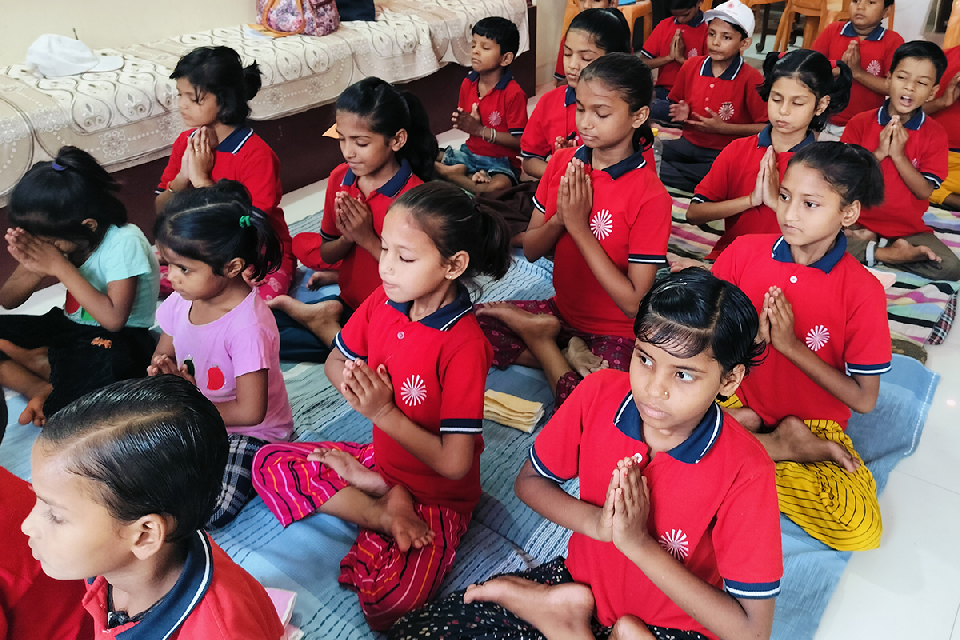 Children at Divine Sanskarshala sitting peacefully with folded hands during a morning meditation and prayer session, practicing mindfulness, discipline, and spiritual values.