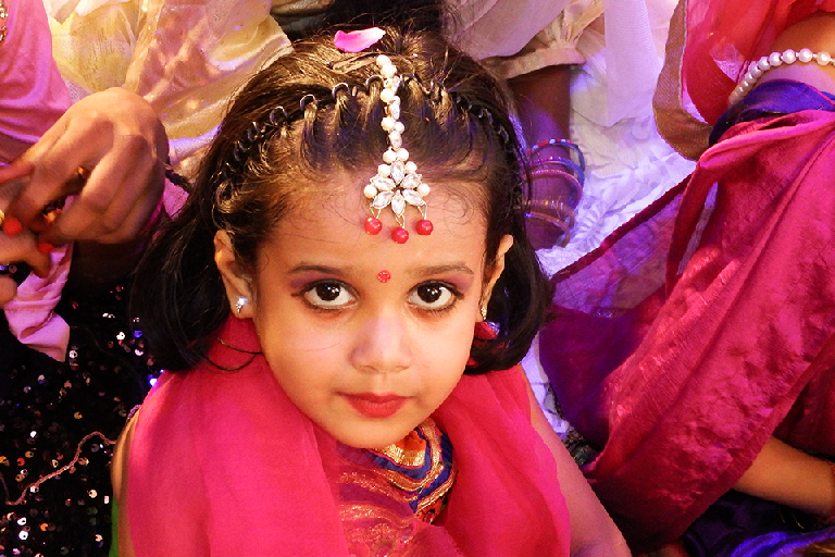 Close-up portrait of a young girl from Divine Sanskarshala dressed in traditional festive attire with elegant jewelry and a decorative headpiece during a Janmashtami celebration.